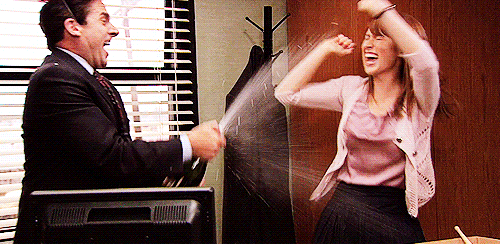 A gif of Michael Scott from "The Office" showering Erin with champagne